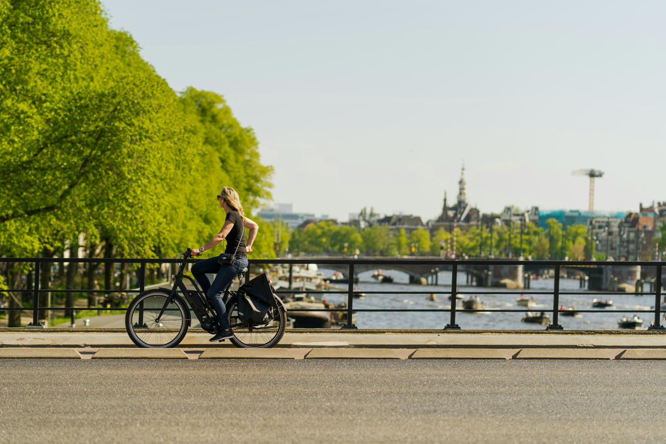 Woman cycling along the Amstel river in Amsterdam on a sunny day